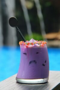 Colorful taro milk tea with sprinkles and ice by poolside, refreshing drink.